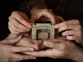 Image of hands with the house-Teatre between them