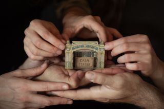 Imatge d'unes mans amb la casa-Teatre entre elles