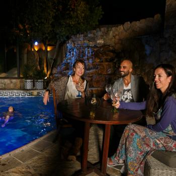 imagen nocturna de grupo de jóvenes tomando una copa ante piscina termal